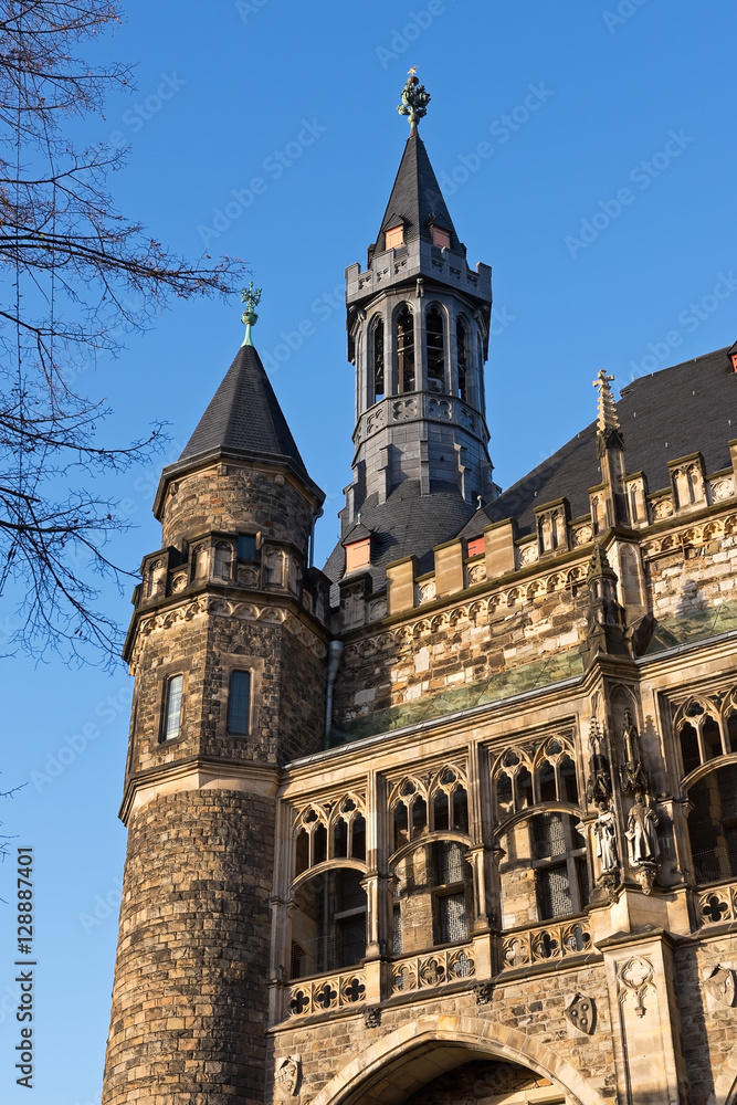 Part of the Aachen City Hall with towers and figures against the blue sky