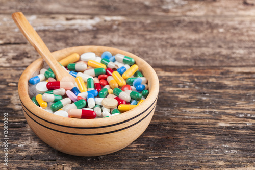 Medical concept the colorful medicine,pills,tablets, spoon wood,bowl wood on wooden background.