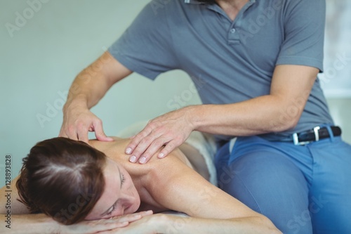 Physiotherapist giving shoulder massage to a woman