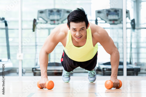 Foto Bodybuilder doing pushups holding dumbbells in hands