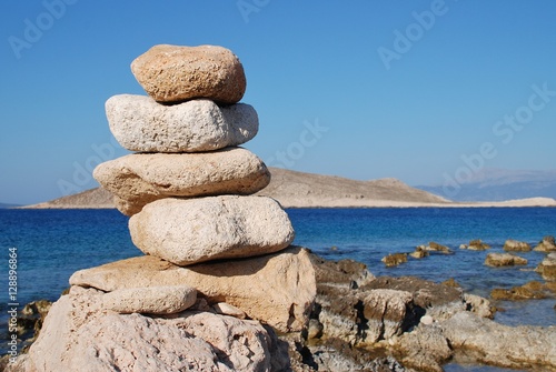 A tower of stones on Ftenagia beach at Emborio on the Greek island of Halki. The uninhabited island of Nissos is in the background.