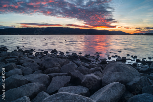 Traumhafter Sonnenuntergang mit Steinen am Seeufer 