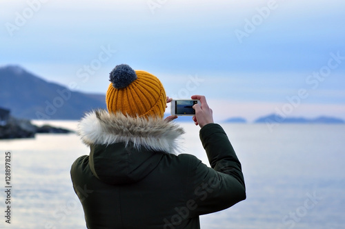A man taking a picture by phone in Oslo during a cold gray winter Day