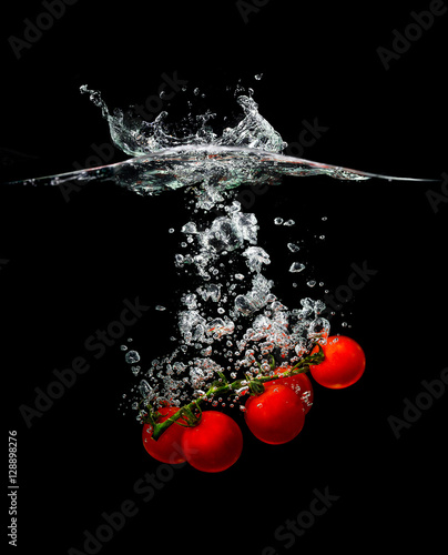 Macro bright tomato in water on a black background. Studio.