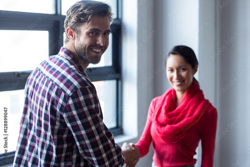 Young colleagues shaking hands in office Young colleagues shaking hands in office