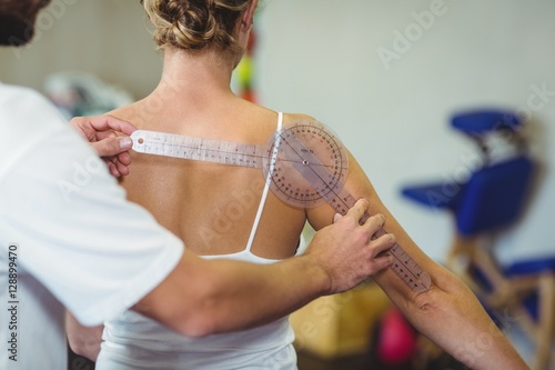 Obraz na plátne Male therapist measuring female patient back with goniometer
