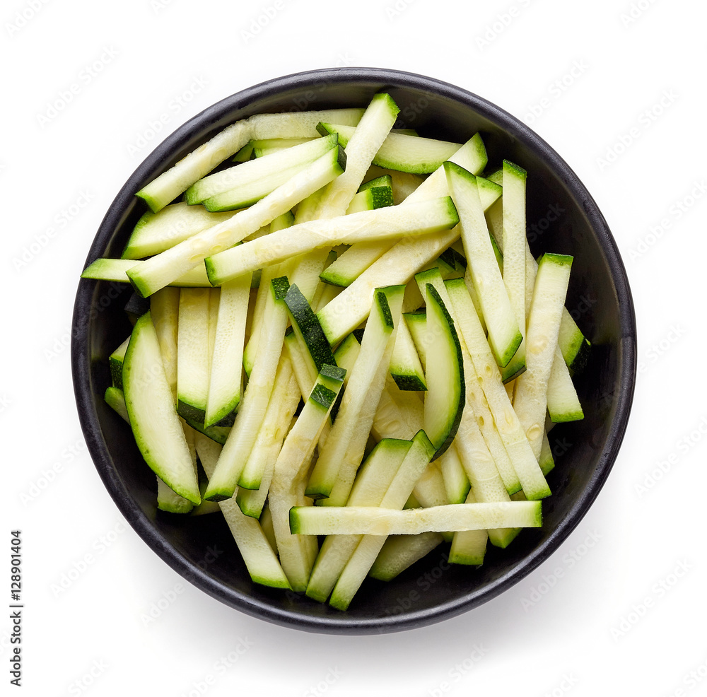 Bowl of fresh zucchini slices isolated on white, from above