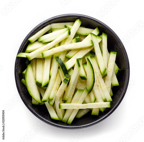 Bowl of fresh zucchini slices isolated on white, from above