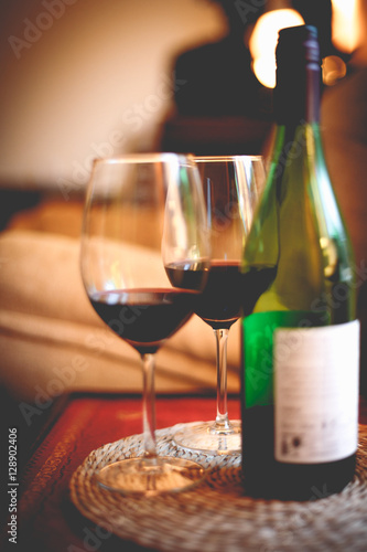 Bottle of red wine with two glasses on red table in dark romanti