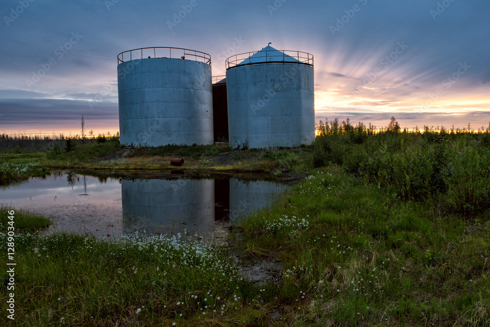 Large tanks at sunset sky background. Indigirka shore. Yakutia. Russia. Large tanks at sunset sky background. Indigirka shore. Yakutia. Russia.