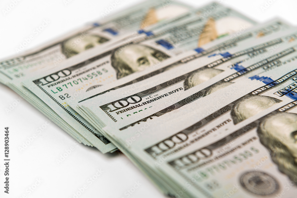 Heap of hundred dollar banknotes on white surface Heap of hundred dollar banknotes on white surface