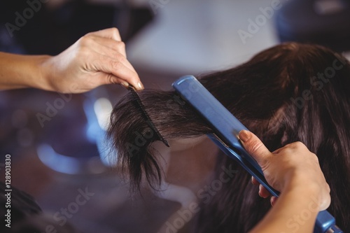 Tableau sur toile Hairdresser straightening the hair of a client