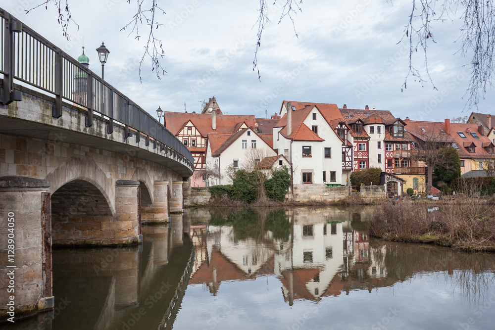 Small German village seen next to a bridge with its reflection i