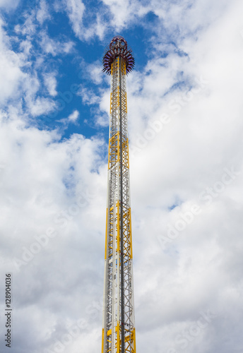 High free fall tower in an amusement park with blue sky and clou