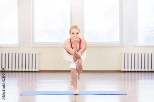 Young fit woman practicing yoga asana garudasana