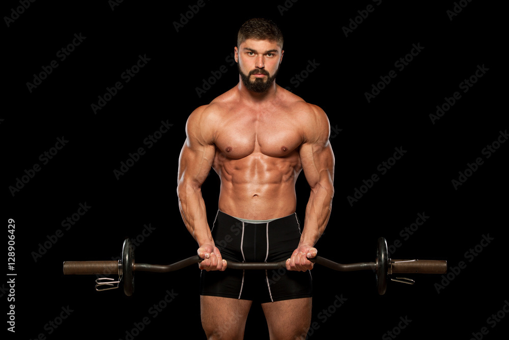 Muscular male athlete is training by lifting the barbell Muscular male athlete is training by lifting the barbell