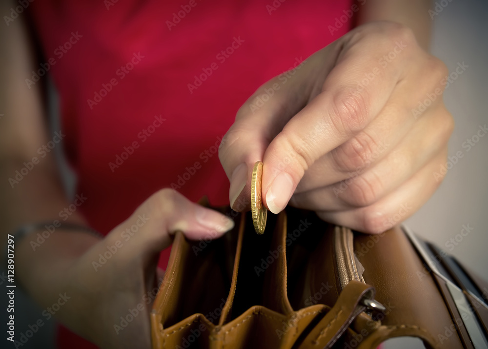 Obraz premium Young woman putting a coin in a purse.