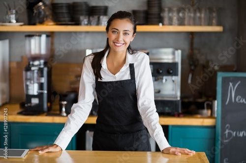 Portrait of smiling waitress standing at counter photo