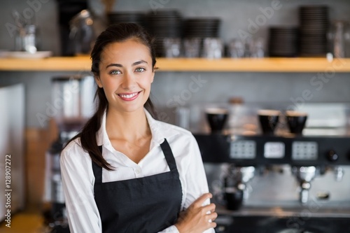 Portrait of smiling waitress standing with arms crossed