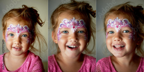 Pretty exciting blue-eyed girl of 2 years with a pink face painting