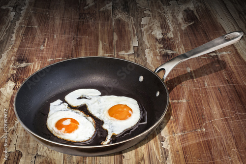 Sunny Side Up Eggs Well Done In Old Heavy Duty Teflon Frying Pan Set On Old Cracked Flaky Wooden Table