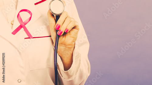 Pink ribbon with stethoscope on medical uniform.
