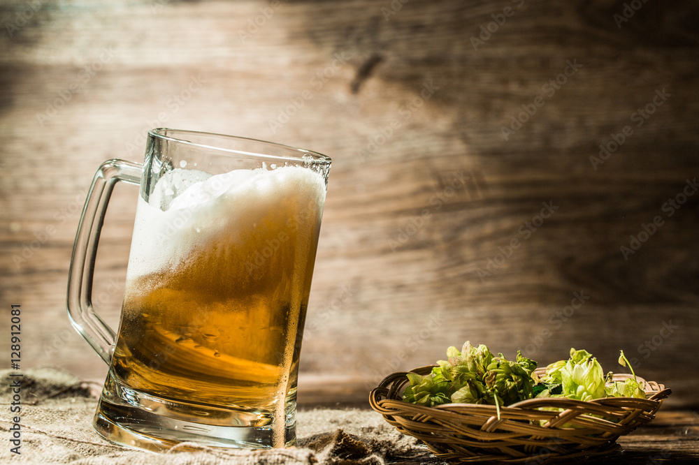 Frothy beer poured from cup standing on linen cloth Frothy beer poured from cup standing on linen cloth