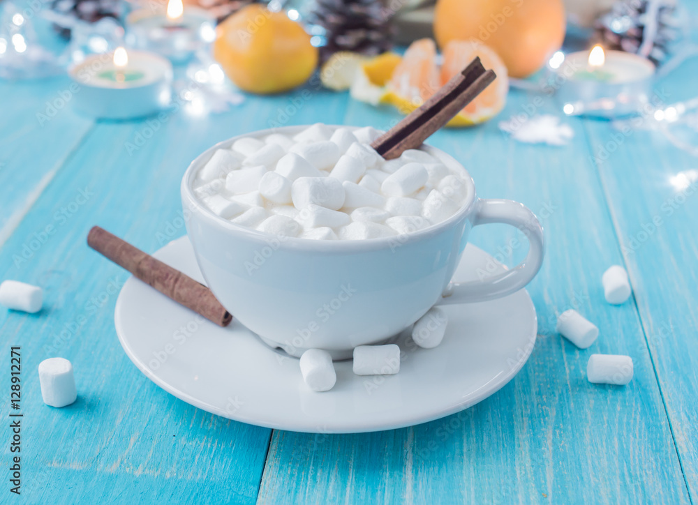 A cup of hot cocoa with marshmallows and sticks of cinnamon on a bright blue wooden background shabby. Shallow Selective focus.
