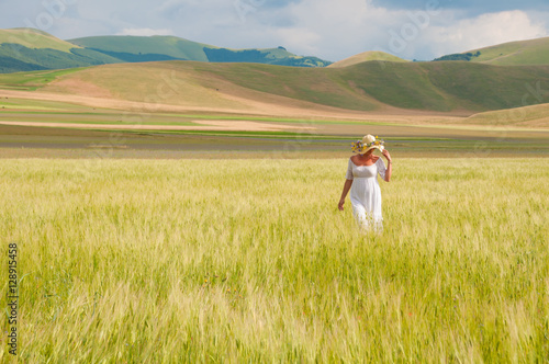 Girl in White dress and straw hat walking among fields in countryside © Maresol