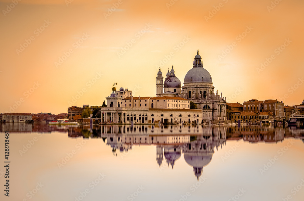 Fototapeta premium Odosobniony bazyliki Di Santa Maria della salut przy pomarańczowymi kolorami odbijał na wodnej powierzchni, Wenecja, Włochy.
