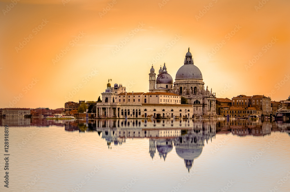 Isolated Basilica di Santa Maria della Salute at orange colors reflected on the water surface, Venice, Italy.