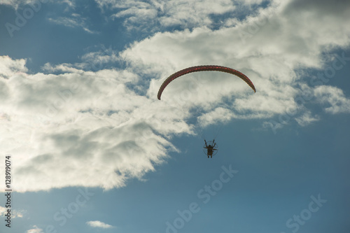 Paramotor flying over the fields in the sky.