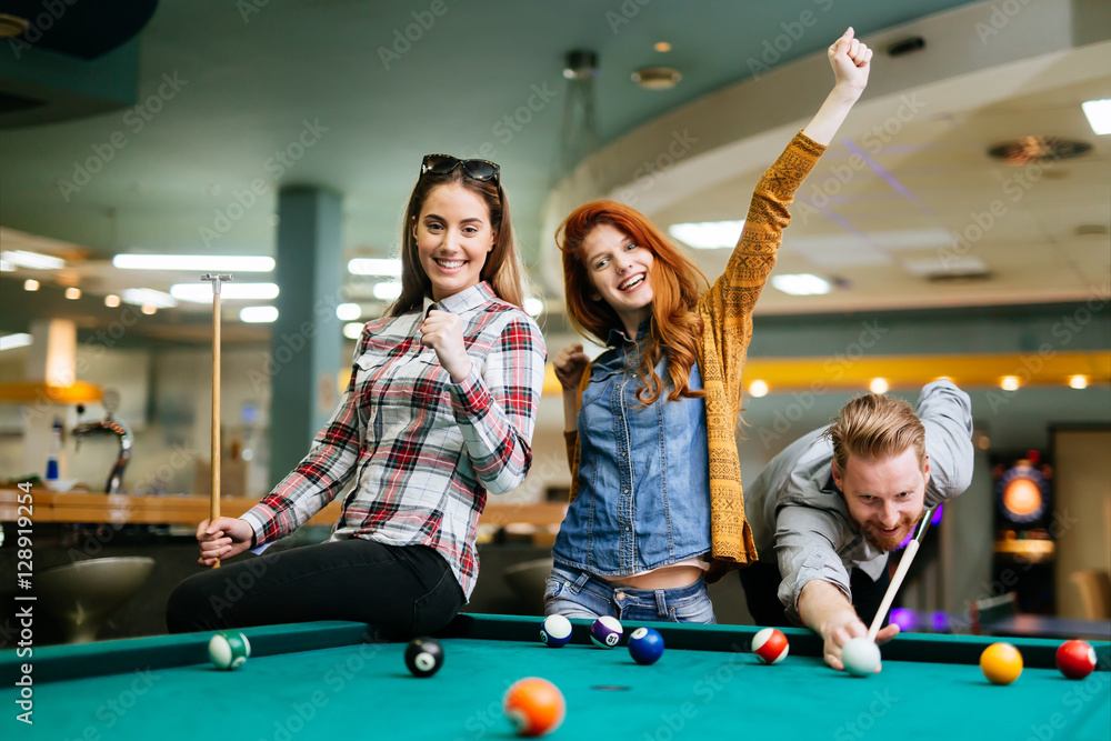 Fototapeta premium Happy friends enjoying playing pool
