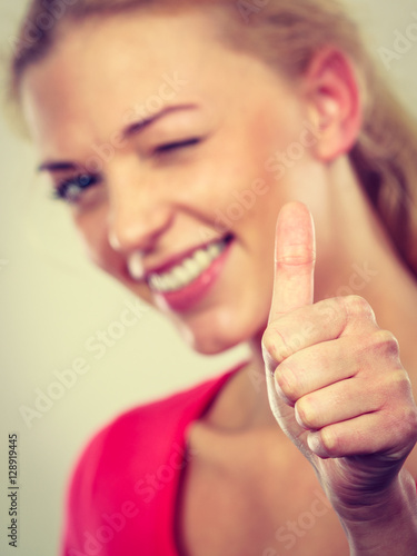 Winking blonde woman showing thumb up