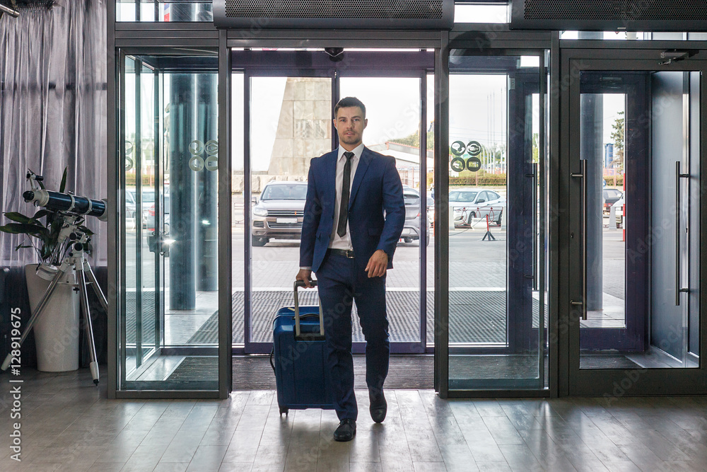 Young businessman with luggage in hotel lobby Young businessman with luggage in hotel lobby