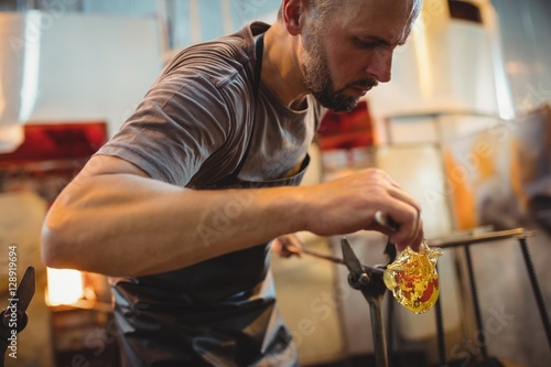 Glassblower shaping a molten glass photo