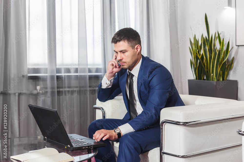Young businessman working at laptop in lobby Young businessman working at laptop in lobby