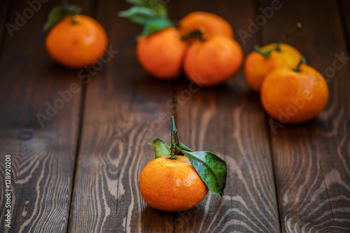 juicy ripe tangerines with leaves on wooden background closeup. health