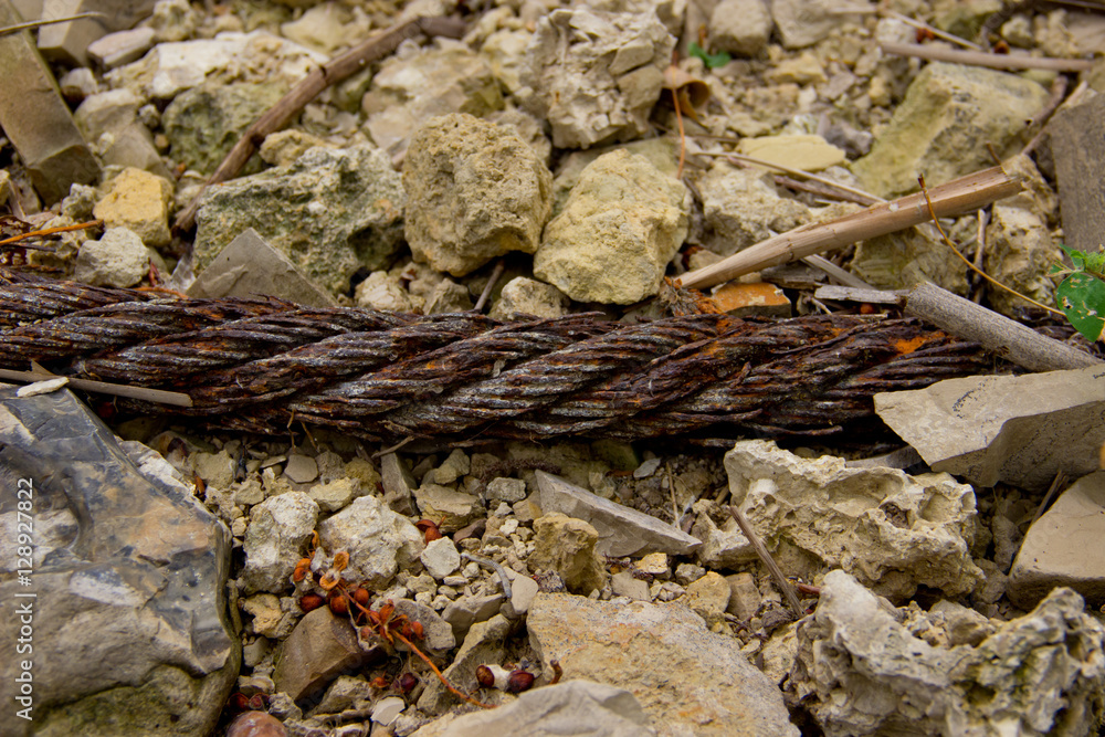 Fototapeta premium Closeup of an old rusty metal rope on the stones as a background