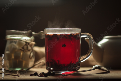 Concept: restaurant menus, healthy eating, homemade, gourmands, gluttony. Hibiscus tea with fruit pieces and sugar in glass jar on vintage wooden background.