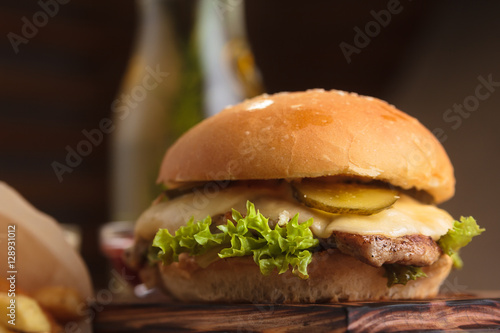 Concept: restaurant menus, healthy eating, homemade, gourmands, gluttony. Classic burger with beef with ingredients and french fries on messy vintage wooden background.