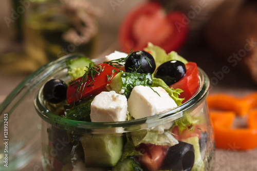 Concept: restaurant menus, healthy eating, homemade, gourmands, gluttony. Greek salad served in glass jar with ingredients on weathered sackcloth background.