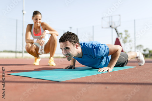 Young, beautiful, fit and healthy personal trainer counting push