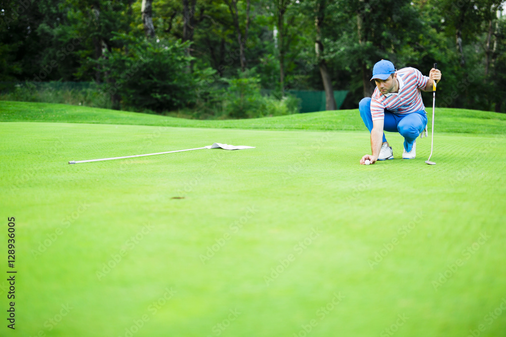Golf player marking ball on the putting green