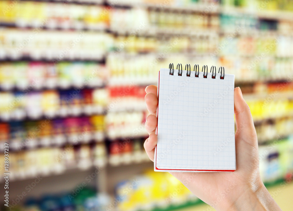 Woman with notebook in store, closeup. Blank paper. Woman with notebook in store, closeup. Blank paper.