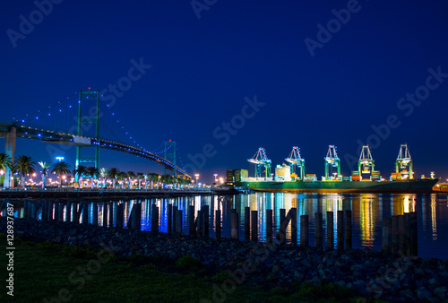 Cargo ship next to bridge at night photo