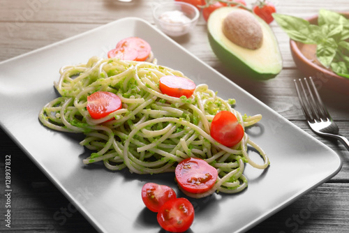 Spaghetti with cherry tomatoes and avocado sauce on wooden table closeup