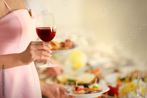 Woman holding glass of red wine on blurred background  close up view