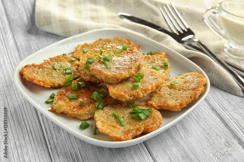 Plate with tasty potato pancakes for Hanukkah on wooden table