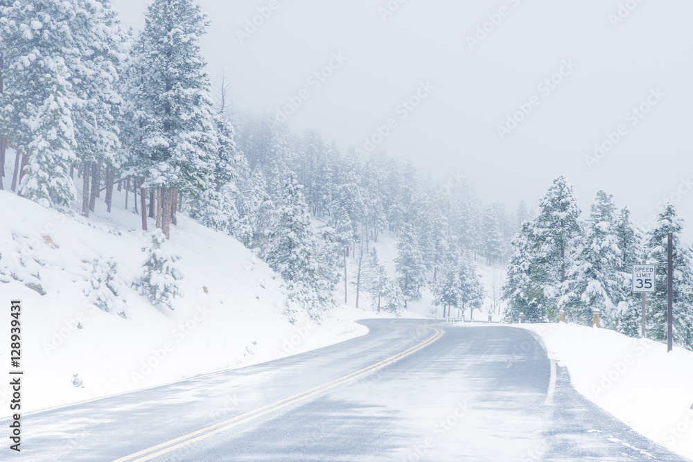 Beautiful winter scene with icy slick road driving situation curving road covered with snow and snowy trees all around